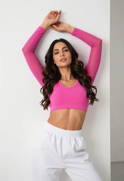 Fit woman in pink sports bra posing against white wall indoors