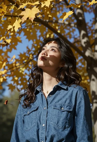 Young woman looking up through autumn leaves dappled sunlight forest setting