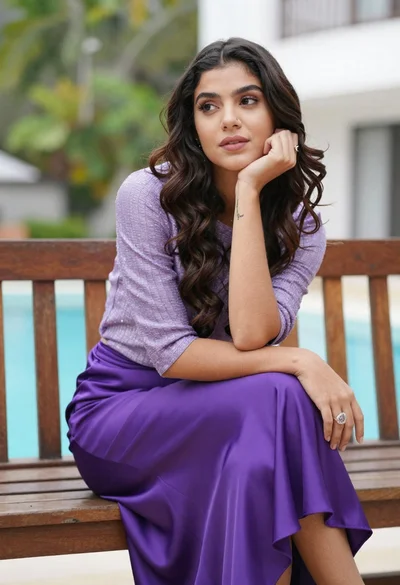 Young woman with dark hair sitting on bench by pool outdoors