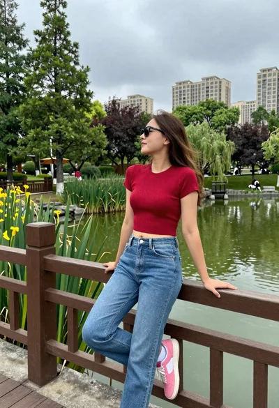 Young woman leaning on bridge railing overlooking green pond in park