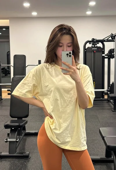 Young woman taking a mirror selfie in a gym setting indoors