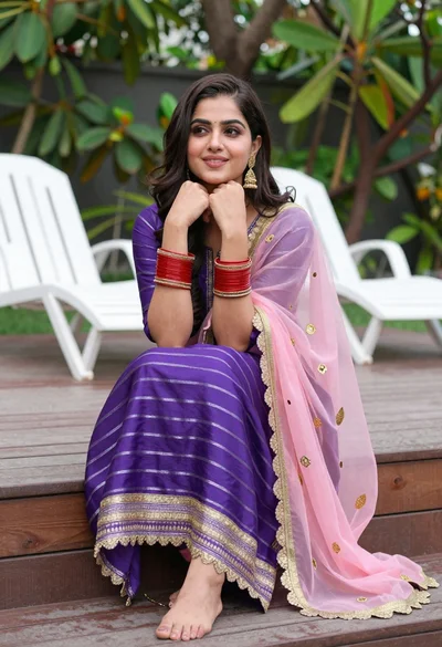 Young woman in purple salwar kameez on wooden garden deck