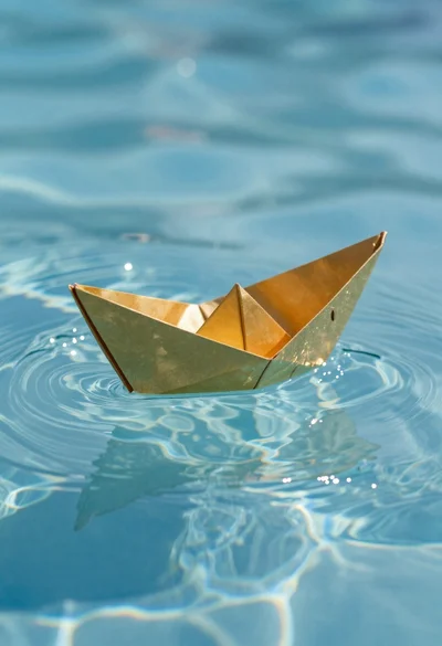 Golden origami boat on clear blue water