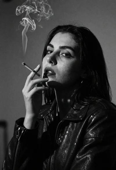 Cinematic black and white portrait of woman smoking cigarette against shadow wall
