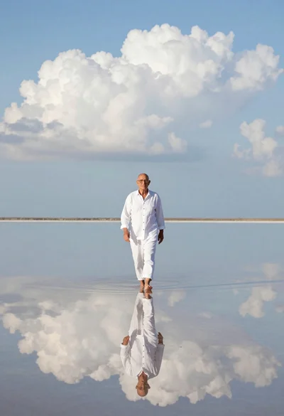Older man walking across still reflective body of water