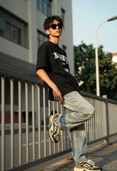 Young man leaning on metal railing in urban setting with golden sunlight
