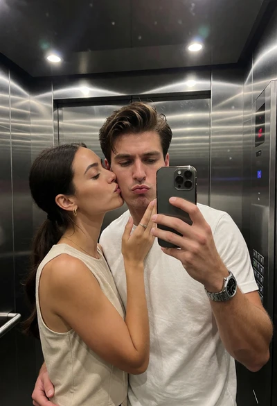 Couple taking a playful mirror selfie inside modern elevator interior