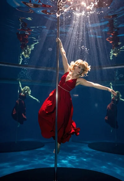 Woman pole dancing underwater in red gown