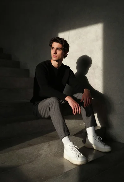Man sitting on concrete steps in dramatic sunlight