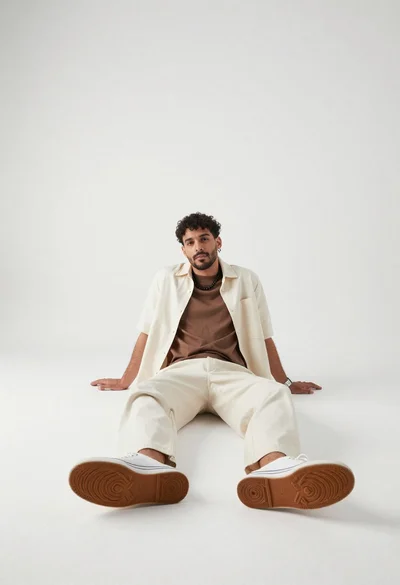 Man sitting on floor in minimalist white studio setting