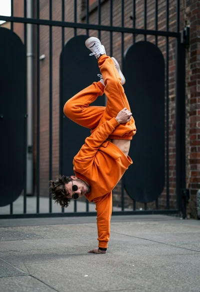 Man performing dynamic breakdancing freeze in an urban alleyway setting
