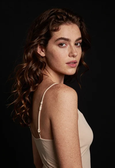 Studio portrait of young woman with wavy brown hair and warm skin tones
