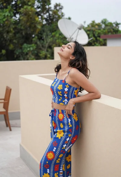Woman in blue floral outfit on rooftop terrace enjoying soft daylight