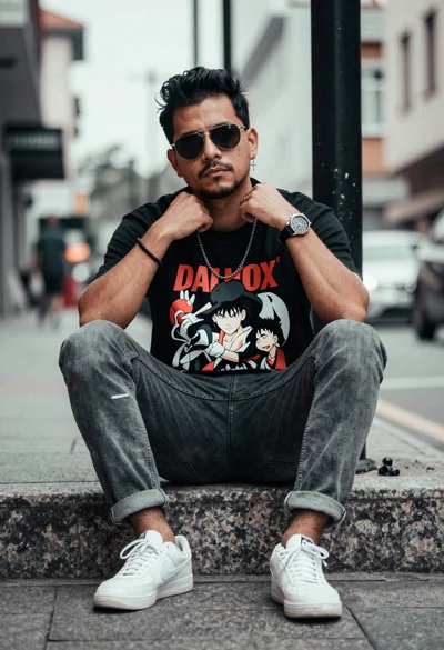 Man sitting on stone ledge in urban street wearing graphic tshirt