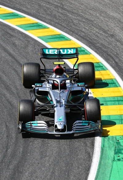 High angle view of silver formula one race car turning on asphalt