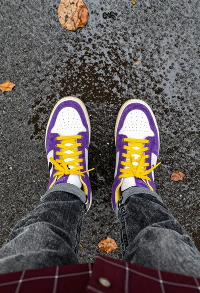 Sneakers on wet pavement with autumn leaves