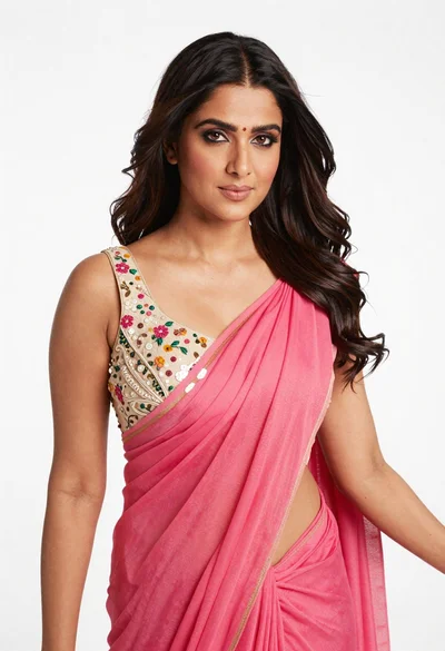 Poised woman in pink saree against a plain white studio background