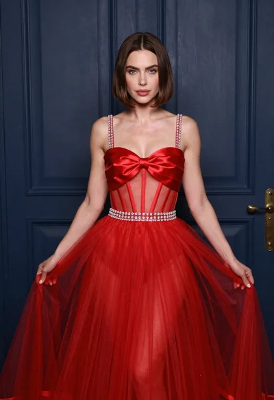 Woman in elaborate red gown standing before dark blue paneled door