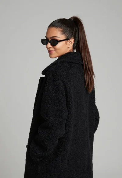 Young woman in black boucle coat looking back over shoulder profile shot