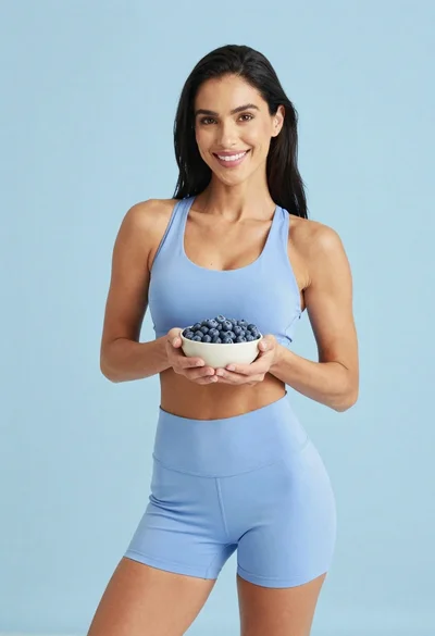 Fit woman in light blue athletic wear holding a bowl of blueberries