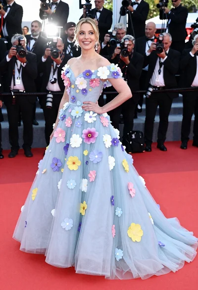 Blonde woman in voluminous blue floral gown on red carpet