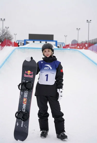 Blonde snowboarder in winter gear standing by halfpipe arena