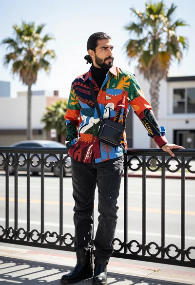 Stylish man leaning on railing in urban setting with palm trees background