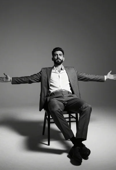 Low angle portrait of bearded man in grey suit reclining on chair