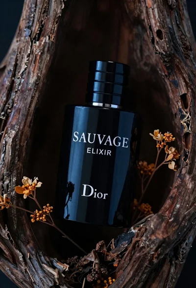 Glossy black dior sauvage elixir perfume bottle in dark wood hollow