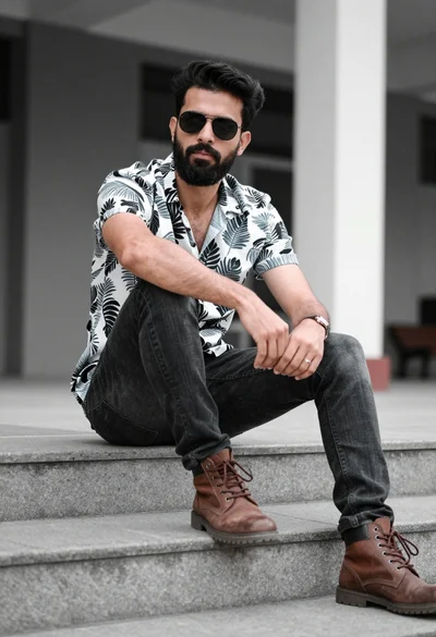 Man sitting casually on concrete steps in an urban setting with blurred