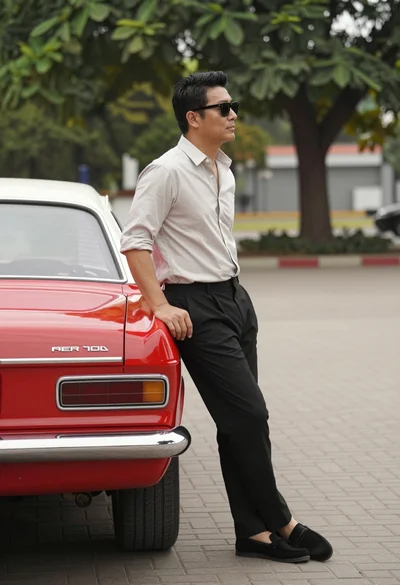 Man leaning against a vintage red car on paved brick area outdoors
