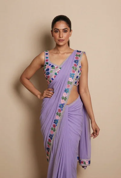 Confident woman in lavender embroidered saree blouse against a beige wall