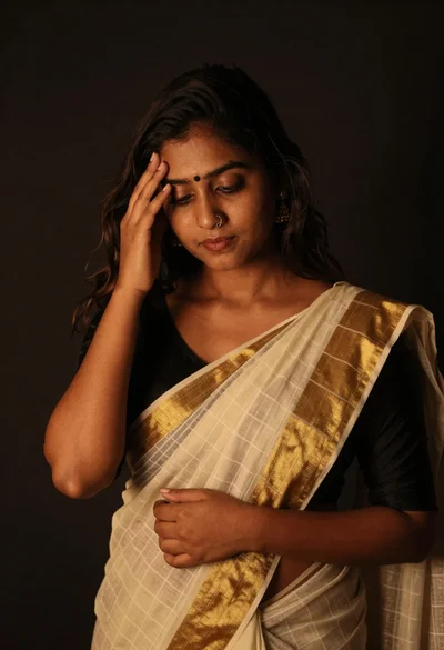 Young woman in traditional saree posing contemplatively against dark background