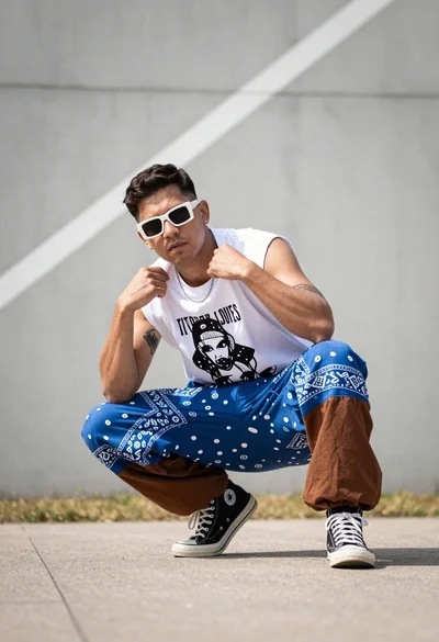 Man crouching in white tshirt against blurred concrete wall outdoors