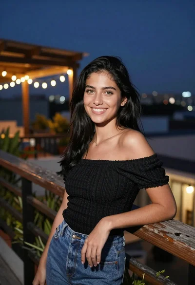 Young woman with black hair smiling on rooftop terrace at night