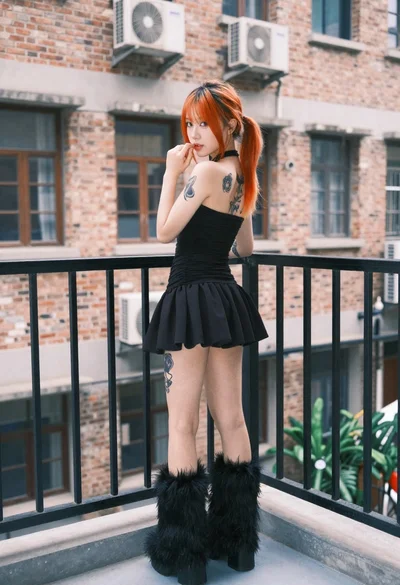Young woman in black mini dress on urban balcony looking back
