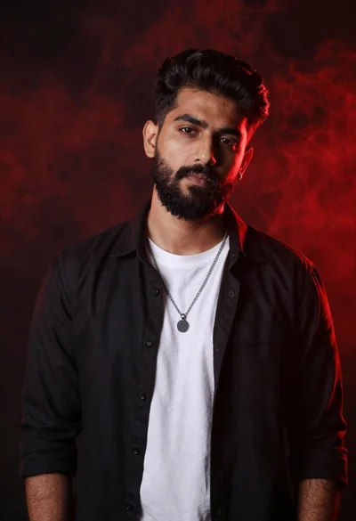 Confident man with dark hair and beard in black shirt against red