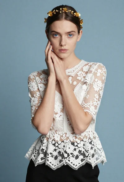 Portrait of young woman with blue eyes wearing white lace top studio