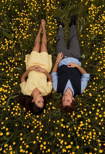 Couple lying in field of yellow flowers viewed from directly above