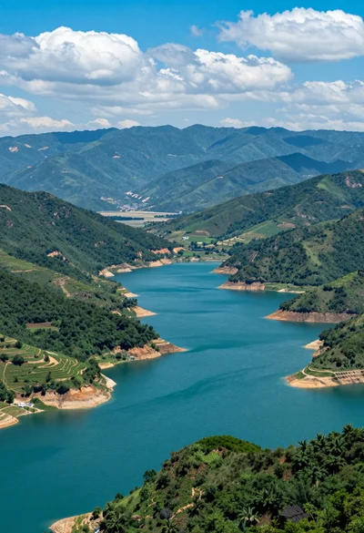 High angle view of vast turquoise reservoir surrounded by rugged green mountains
