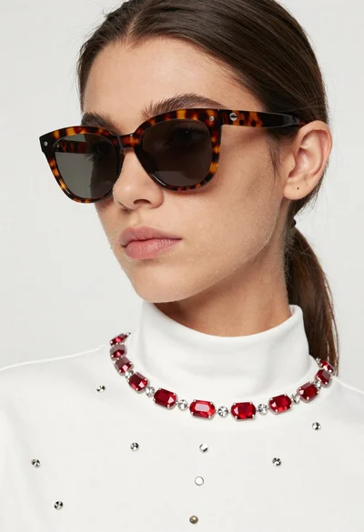 Close up portrait of woman in white top with red gemstones