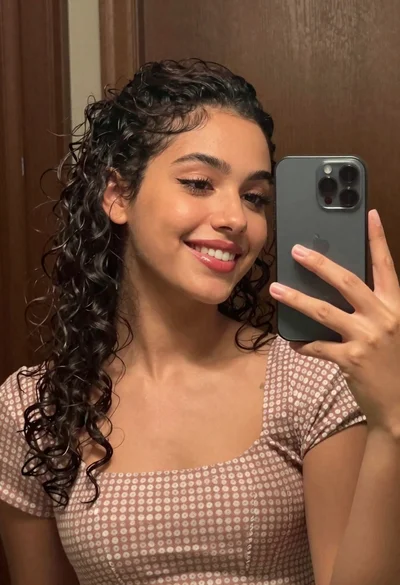 Young woman taking a mirror selfie in front of dark wood panels