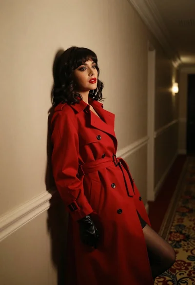 Woman in red trench coat leaning against hallway wall cinematic portrait