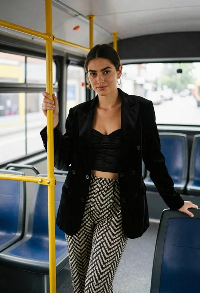 Young woman in black blazer standing inside public transit bus