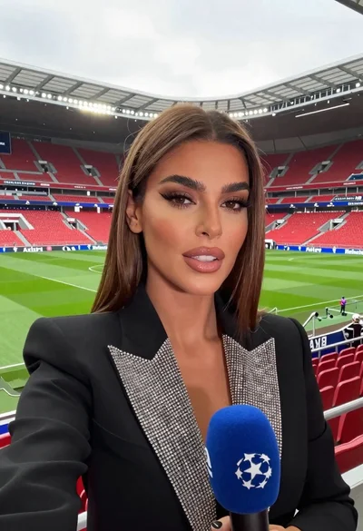 Woman taking a selfie in large football stadium with red seats