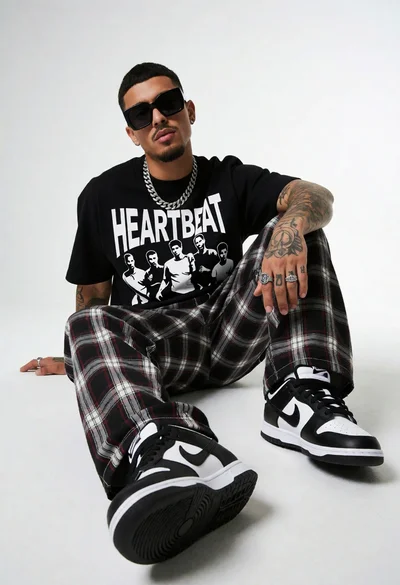 Young man seated on white floor wearing graphic tshirt and sneakers