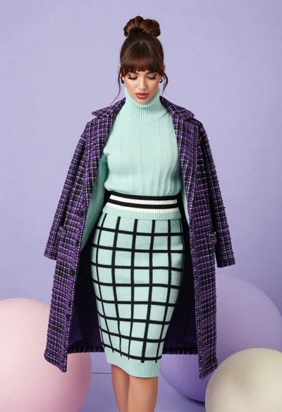 Brunette woman in mint green knit set against pastel purple spheres