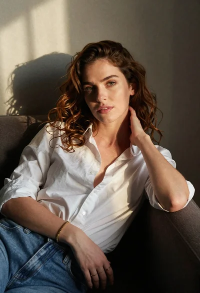 Woman with chestnut hair reclining on dark couch indoors