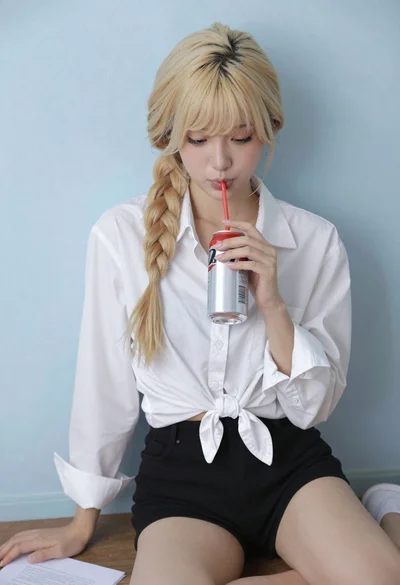 Blonde woman with side braid drinking from soda can indoors