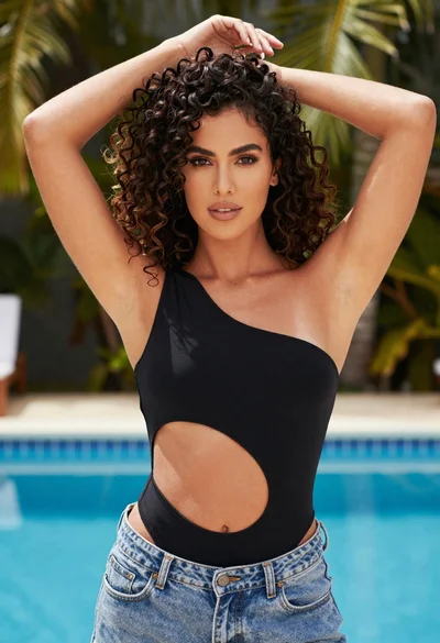 Confident woman in black bodysuit near blue swimming pool outdoors